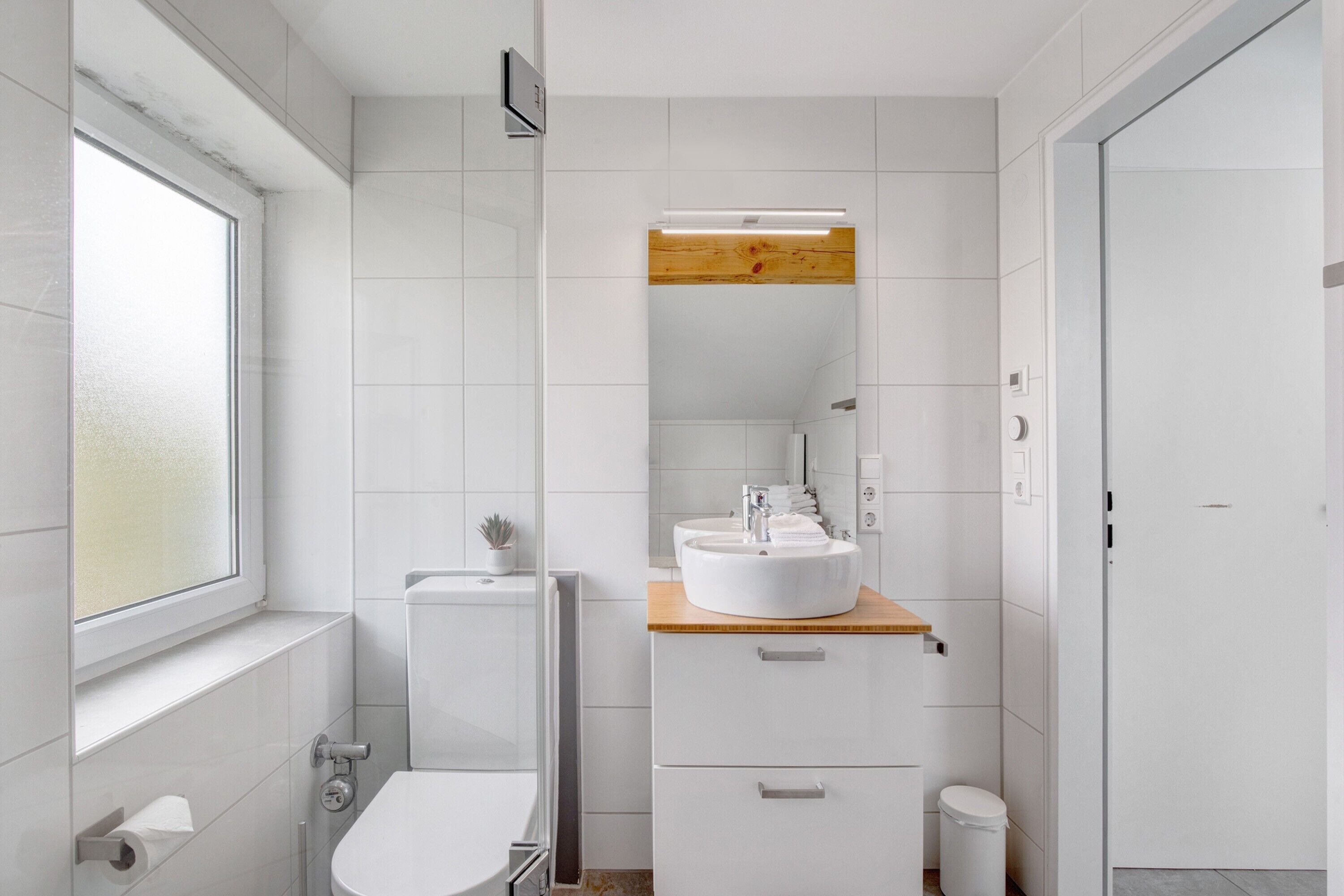 A modern bathroom with a toilet, sink, and mirror.