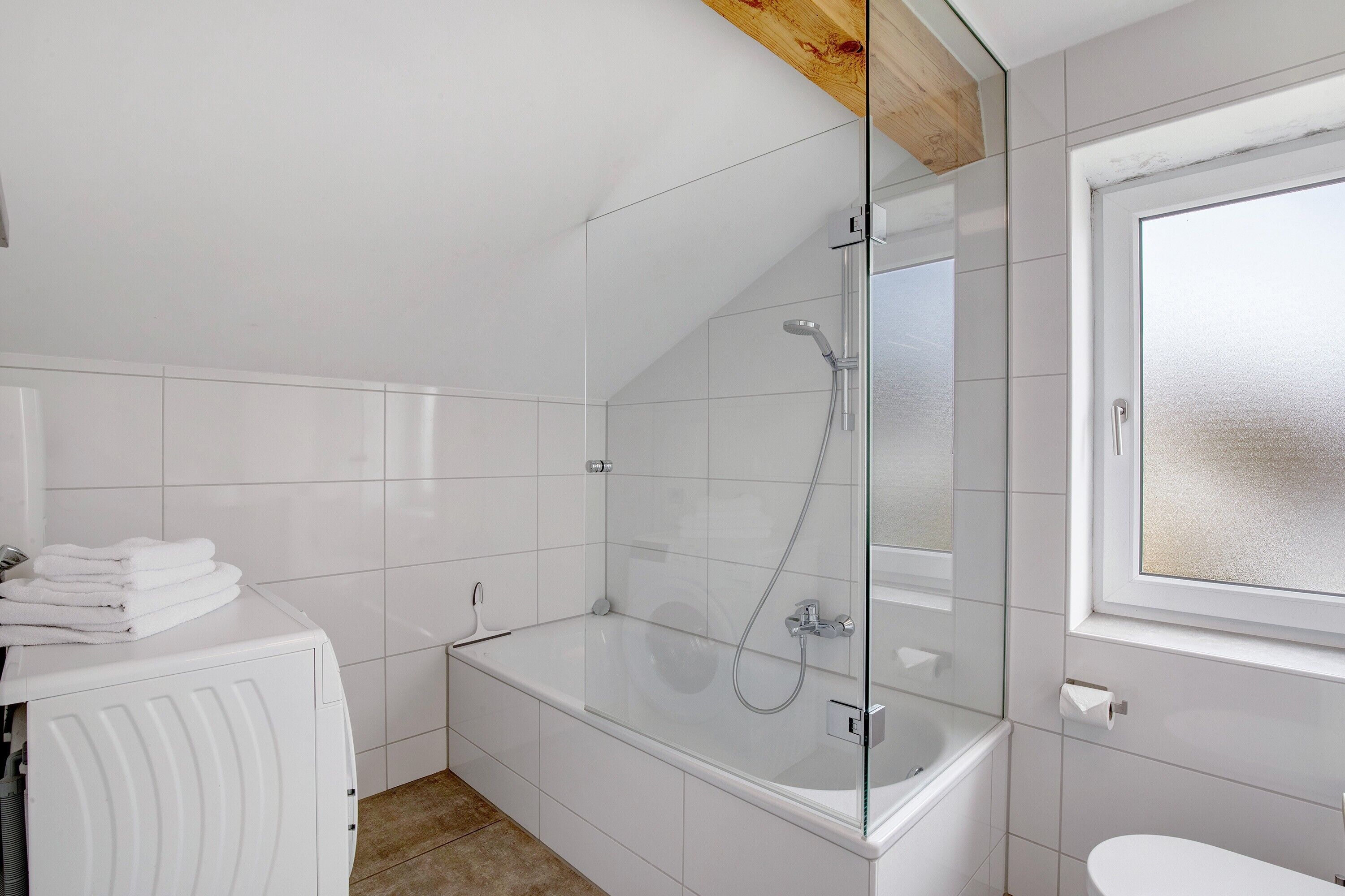 Un baño moderno con cabina de ducha de vidrio, una bañera blanca y un inodoro.