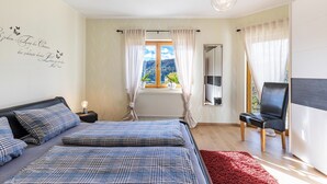 A bedroom with a bed, a chair, a window with curtains, and a view of the outdoors. - Apartment "Südalb" with Shared Garden & Wi-Fi (Albstadt)
