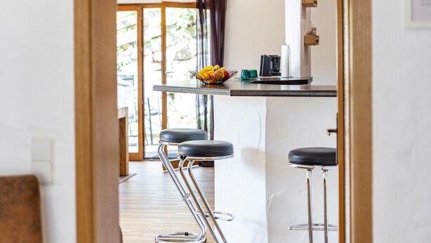 A modern kitchen with a bar area, including stools and a fruit bowl. - Apartment "Südalb" with Shared Garden & Wi-Fi (Albstadt)