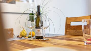 Una mesa de madera con una botella de vino, dos copas de vino y una planta en maceta.