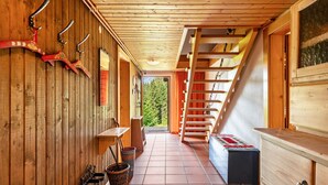 A wooden interior with a staircase, wooden walls, and a view of greenery outside.