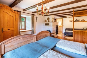 Una habitación con cama de madera, candelabro, chimenea y armario de madera.