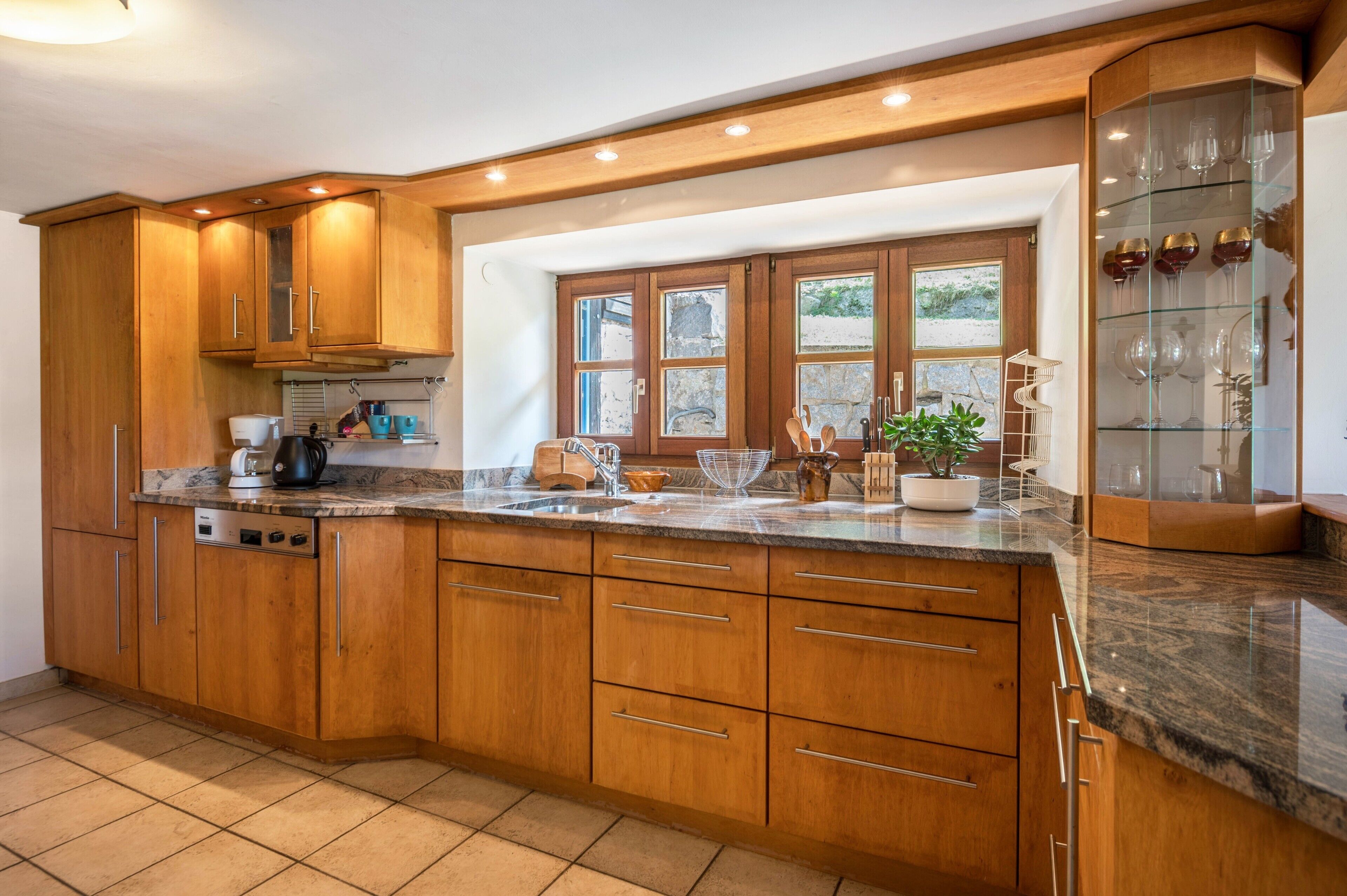 A kitchen with wooden cabinets, a granite countertop, and a built-in wine display.