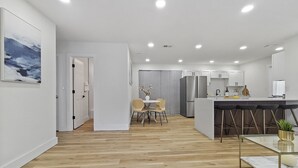 A modern kitchen with white cabinets, a stainless steel refrigerator, and a bar area with stools. - Wilderness Escape, by Breathtaking Natl Park (Tampa)