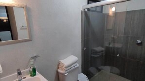 A bathroom with a white sink, mirror, and toilet. There is a glass shower enclosure and a toilet paper roll on the floor. - Excelent apartment, near Downton and Zapopan (Zapopan)