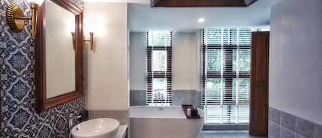 Une salle de bain avec une baignoire sur pieds, un grand miroir et des carreaux décorés.
