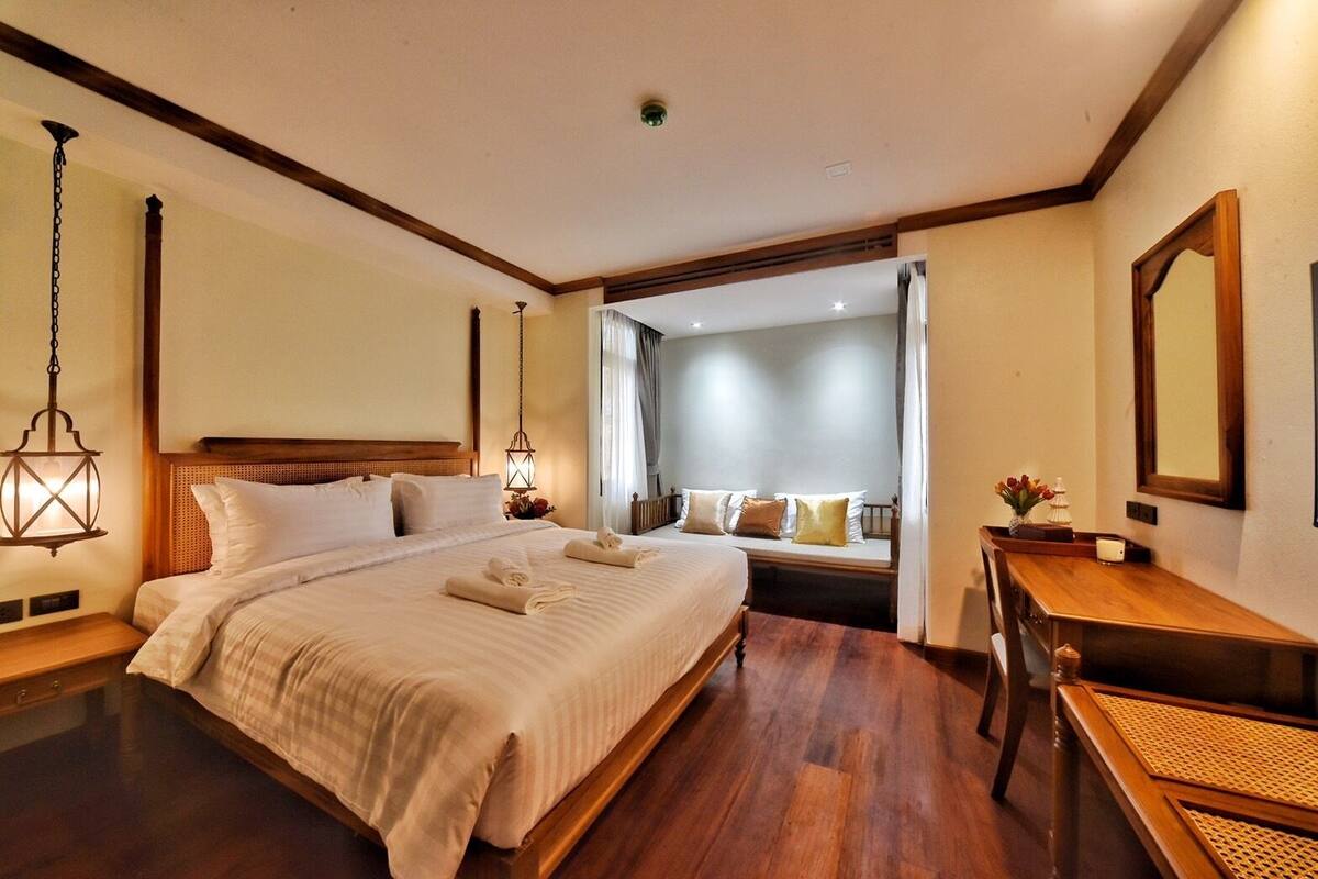 Une chambre d’hôtel avec un grand lit, des tables de chevet, un bureau et un miroir.
