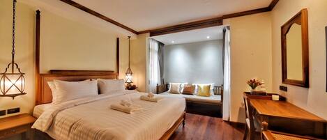 Una habitación de hotel con una cama grande, mesitas de noche, un escritorio y un espejo.