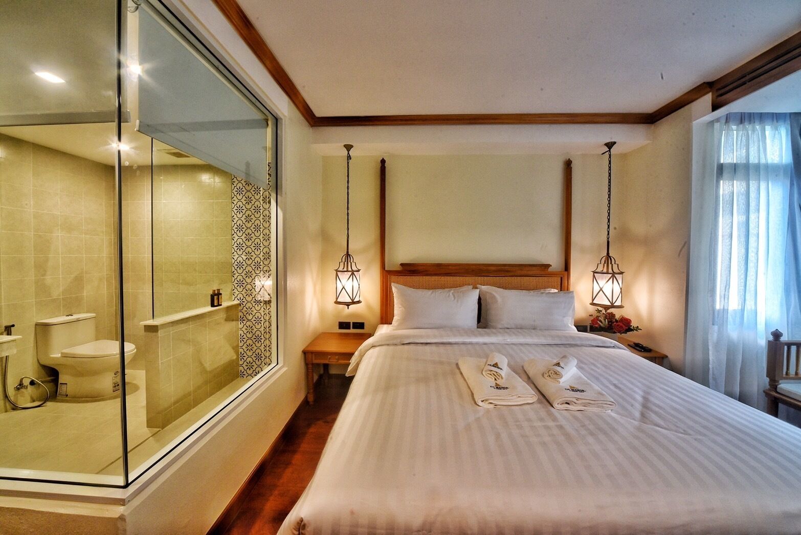 A hotel room with a large bed, a glass shower enclosure, and two bedside lamps.