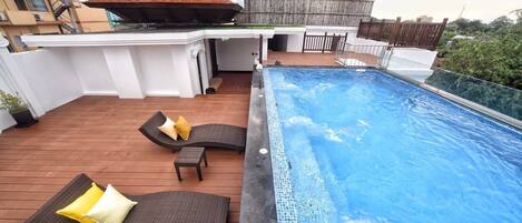 A rooftop pool area with lounge chairs and a small table.