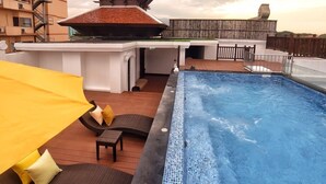 Área de piscina no terraço com hidromassagem, espreguiçadeiras e uma estrutura em estilo pagoda.