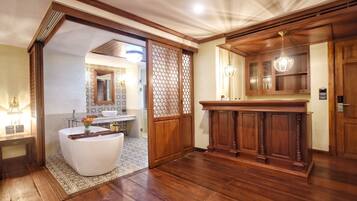 A spacious bathroom with a freestanding bathtub, a wooden vanity, and a large mirror.