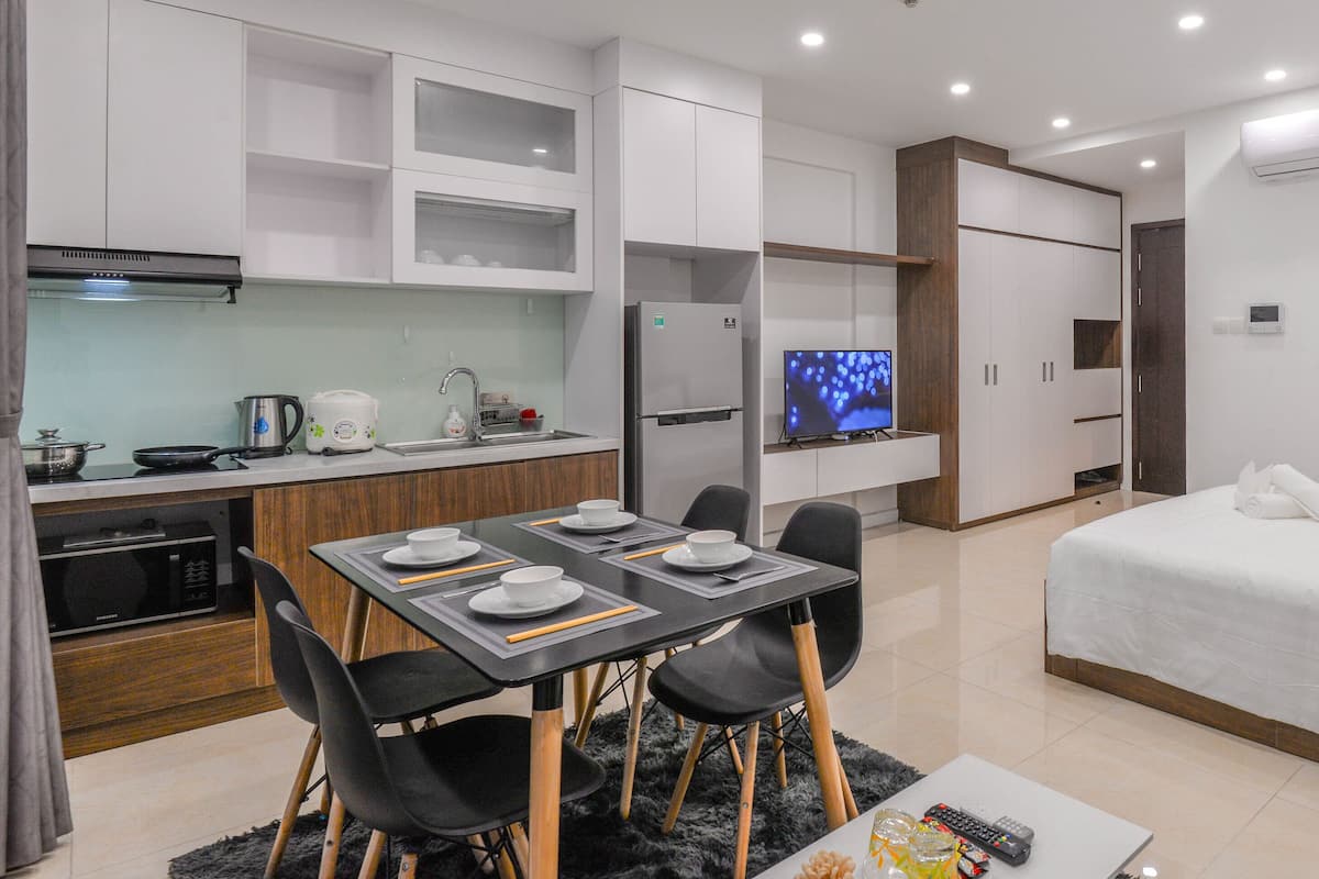 A modern hotel room with a kitchenette, a dining area, and a bed.
