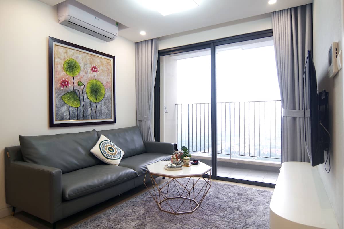 A modern living room with a grey sofa, a coffee table, and a large window with a view.
