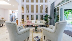 Una sala de estar moderna con un ventanal grande, un sofá, dos sillones y una mesa de centro de vidrio.