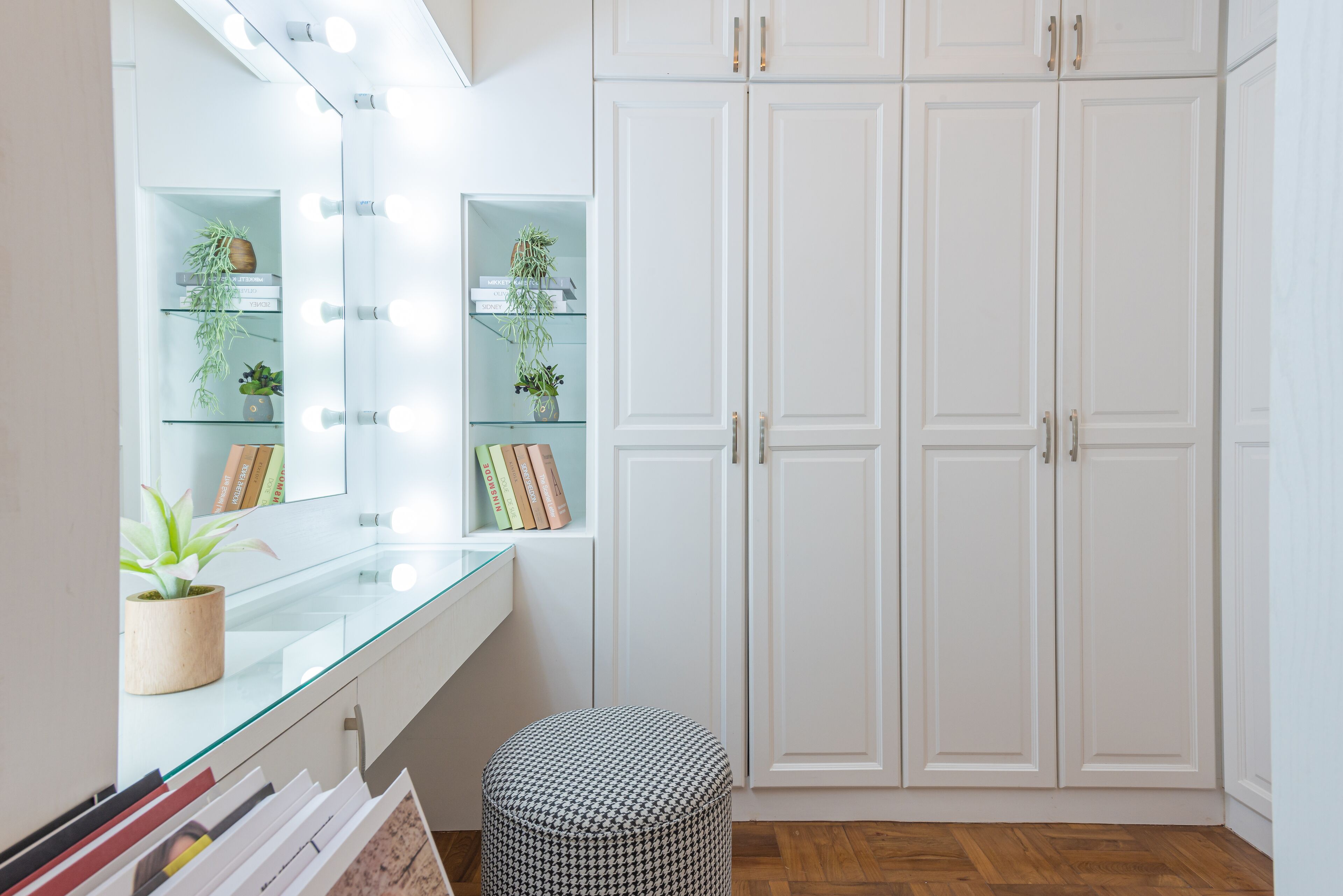 A room with a vanity mirror, shelves with plants, and a wardrobe.