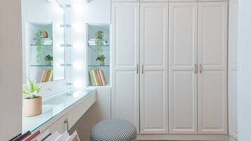 A room with a vanity mirror, shelves with plants, and a wardrobe.