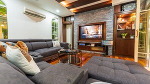 Una sala de estar moderna con un sofá gris, una mesa de centro, un televisor de pantalla plana y una pared de acento de piedra.