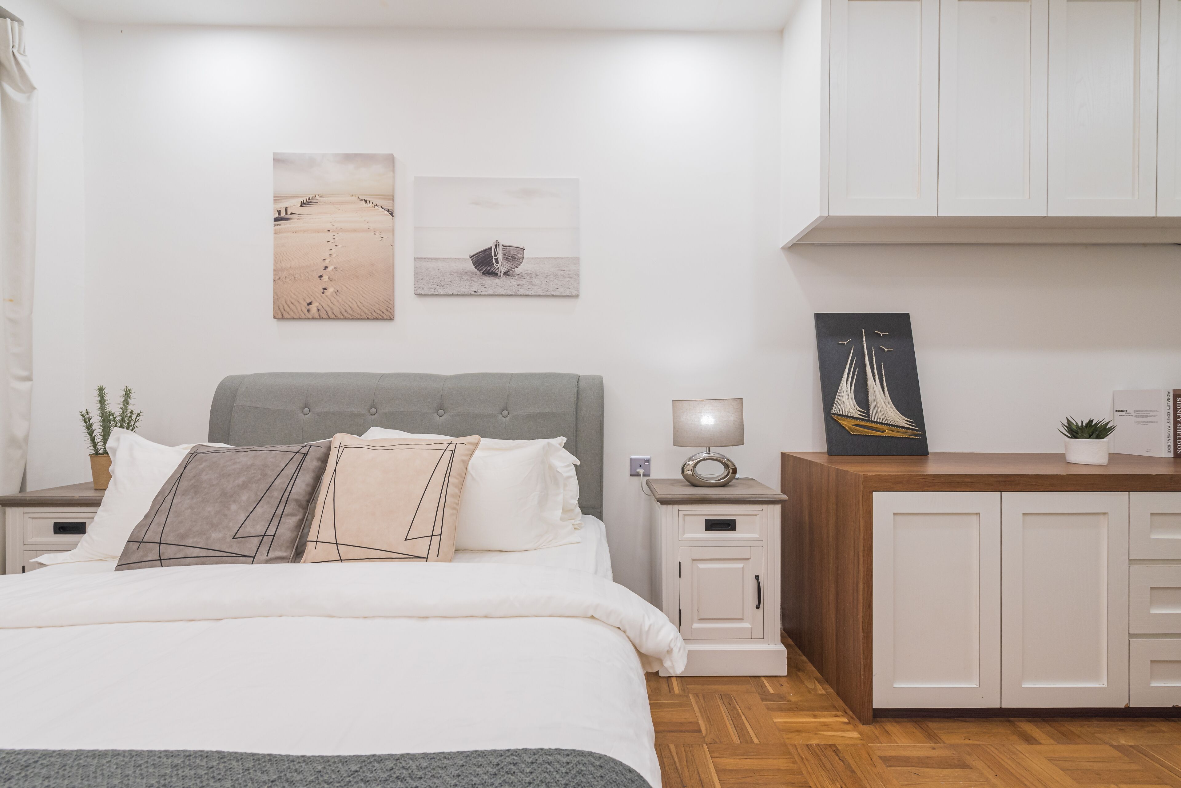 A bedroom with a bed, nightstands, a dresser, and artwork on the wall.