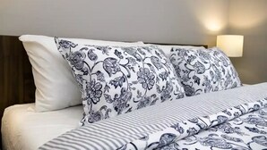 Ein Bett mit gemusterten Betttextilien und einer Nachttischlampe.