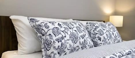 A bed with patterned bedding and a bedside lamp.
