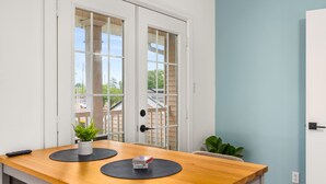 Une cuisine moderne avec un plan de travail en bois, deux sets de table noirs, une plante en pot et une télécommande.