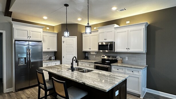 A modern kitchen with a central island, stainless steel appliances, and pendant lighting. - Round Mountain Get Away! (Conway)