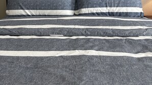 A bed with a dark wooden headboard and gray bedding with white stripes. - Round Mountain Get Away! (Conway)