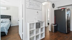A modern kitchen with a stainless steel refrigerator, a white shelving unit, and a welcome sign. - Texas Med Center Stunning & Vibrant Stay (Houston)