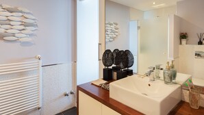 A modern bathroom with a white sink, a mirror, and decorative fish wall art. - Apartment with great sea views on the beach (Marbella)