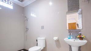 A modern bathroom with a toilet, shower, sink, and mirror. - The Kanjeng Hotel Kuta (Kuta)