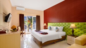 A hotel room with a bed, bedside tables, a desk, and a view of the outdoors. - The Kanjeng Hotel Kuta (Kuta)