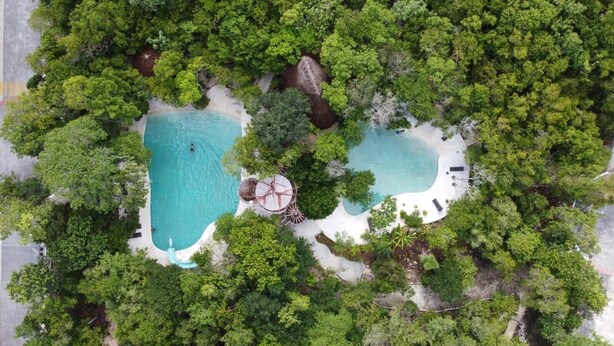 An aerial view of a resort with two swimming pools surrounded by dense greenery and white sand. - Casa en Riviera Maya con alberca privada (Puerto Morelos)