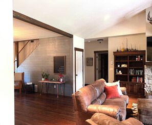 Cozy living area with a leather sofa, bookshelf, and staircase.