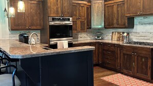 Una cucina moderna con mobili in legno, una grande isola e luci a sospensione.