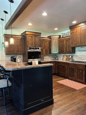 Enjoy cooking in this well-equipped kitchen with a large island, sink, and stainless steel range hood.