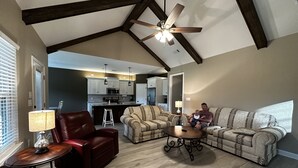 A spacious living room with a high ceiling, a ceiling fan, and a view into the kitchen. - Round Mountain Lazy Days (Conway)
