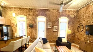 Un salon chaleureux avec un mur en pierre, un canapé, une table basse et un téléviseur.