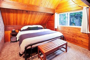 Camera da letto accogliente in legno con un letto, una panca e una finestra vista foresta.