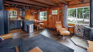 A cozy cabin interior with a dining area, seating, and a stone fireplace.