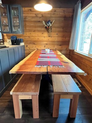 Un tavolo da pranzo in legno con panche, un bicchiere d'acqua e un elemento decorativo a parete.