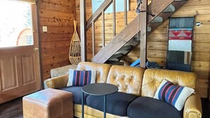 A wooden cabin interior with a sofa, ottoman, and a small table.