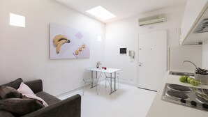 A modern kitchen with a white countertop, a stove, and a dining area with a table and chairs. - WHITE HOUSES, Modern and functional studio apartment (bologna)