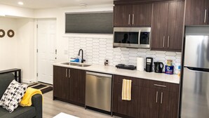 A modern kitchen with dark wood cabinets, stainless steel appliances, and a white tiled backsplash. - Amazing Basement Suite With a Dedicated Workspace (Airdrie)