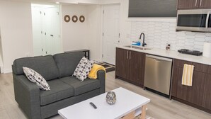 A modern kitchen with a built-in microwave, a dishwasher, and a sink with a hexagonal backsplash. - Amazing Basement Suite With a Dedicated Workspace (Airdrie)