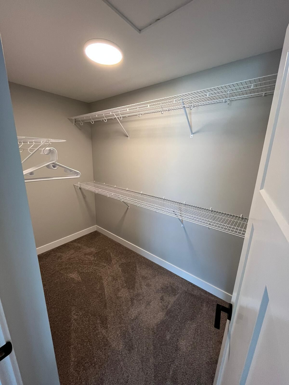 Un dressing avec deux étagères en fil de fer et un luminaire au plafond.