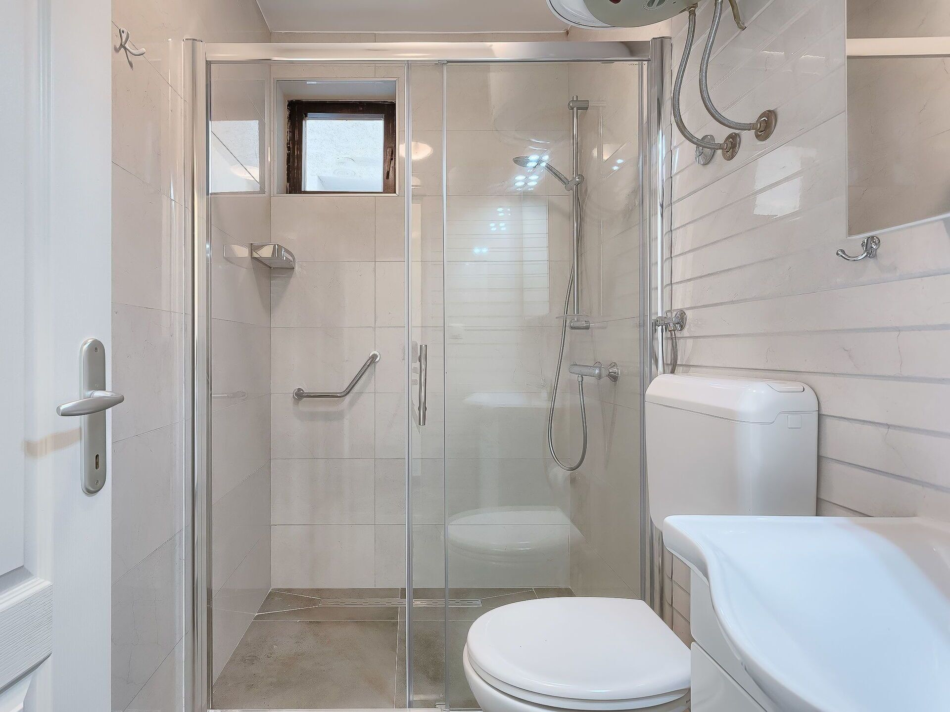 Ein modernes Badezimmer mit einer Glaskabine zur Dusche, einer weißen Toilette und einer Glastür.