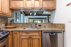 A kitchen with wooden cabinets, granite countertops, a stainless steel dishwasher, and a built-in oven.