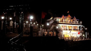 A multi-story building with a traditional architectural style, featuring balconies and a flag on top. - The Parijat Retreat (Bhikyasain)